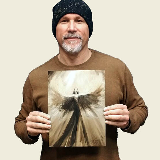 Tom holding one of the angel paintings he gives away in the Be The Angel project