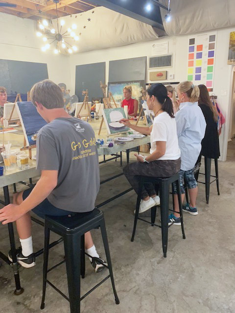 Person concentrating on their canvas at a paint party