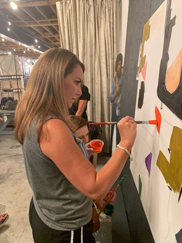 Adult mixing paint colors at their easel