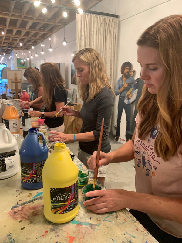 Group of friends gathered around a table painting