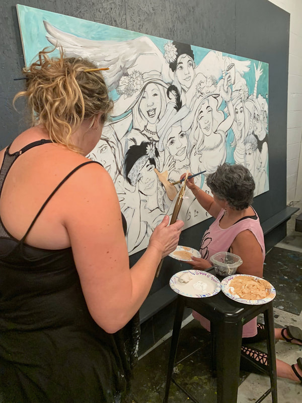 Two friends laughing while painting their canvases