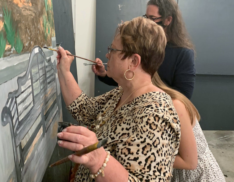 Participants painting together at a mural event.