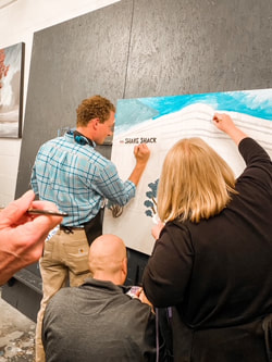 Participants signing the finished mural canvas.